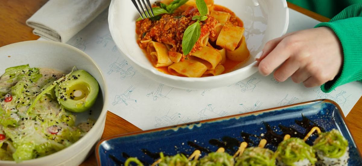 Delicious pasta with fresh basil and avocado salad served in an inviting setting. Perfect for health-conscious diners.