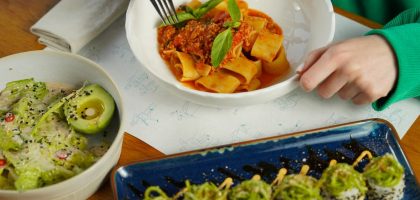 Delicious pasta with fresh basil and avocado salad served in an inviting setting. Perfect for health-conscious diners.