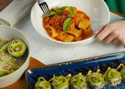 Delicious pasta with fresh basil and avocado salad served in an inviting setting. Perfect for health-conscious diners.