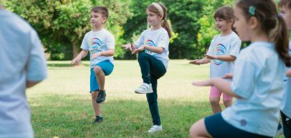 Group of children playing and exercising outdoors in a sunny park setting.
