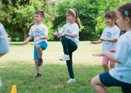 Group of children playing and exercising outdoors in a sunny park setting.