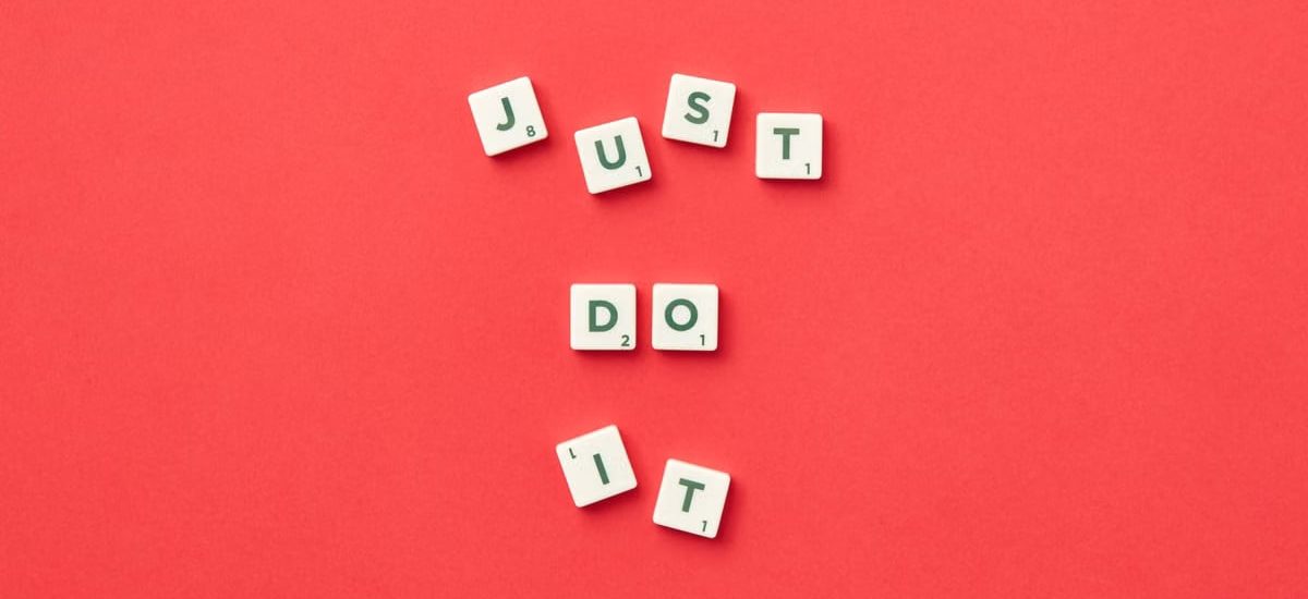 Motivational phrase 'Just Do It' spelled with Scrabble letters on a red background.