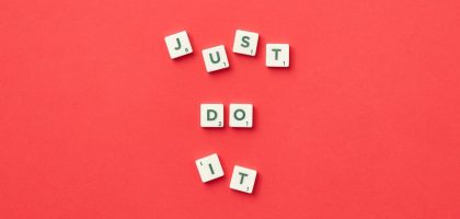 Motivational phrase 'Just Do It' spelled with Scrabble letters on a red background.