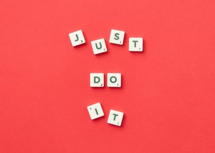 Motivational phrase 'Just Do It' spelled with Scrabble letters on a red background.